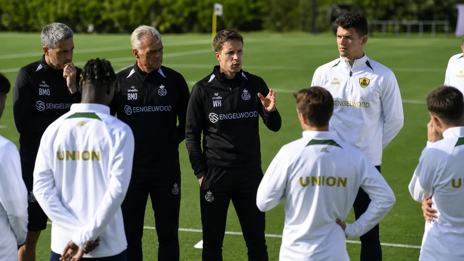 Stafleden geven aanwijzingen aan een groep Union-spelers tijdens een training.