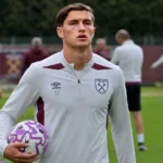 Een voetbaltraining op het complex van West Ham United met spelers en staf op de achtergrond.
