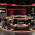 Een verlichte voetbaltelevisiestudio met camera's en een discussietafel.