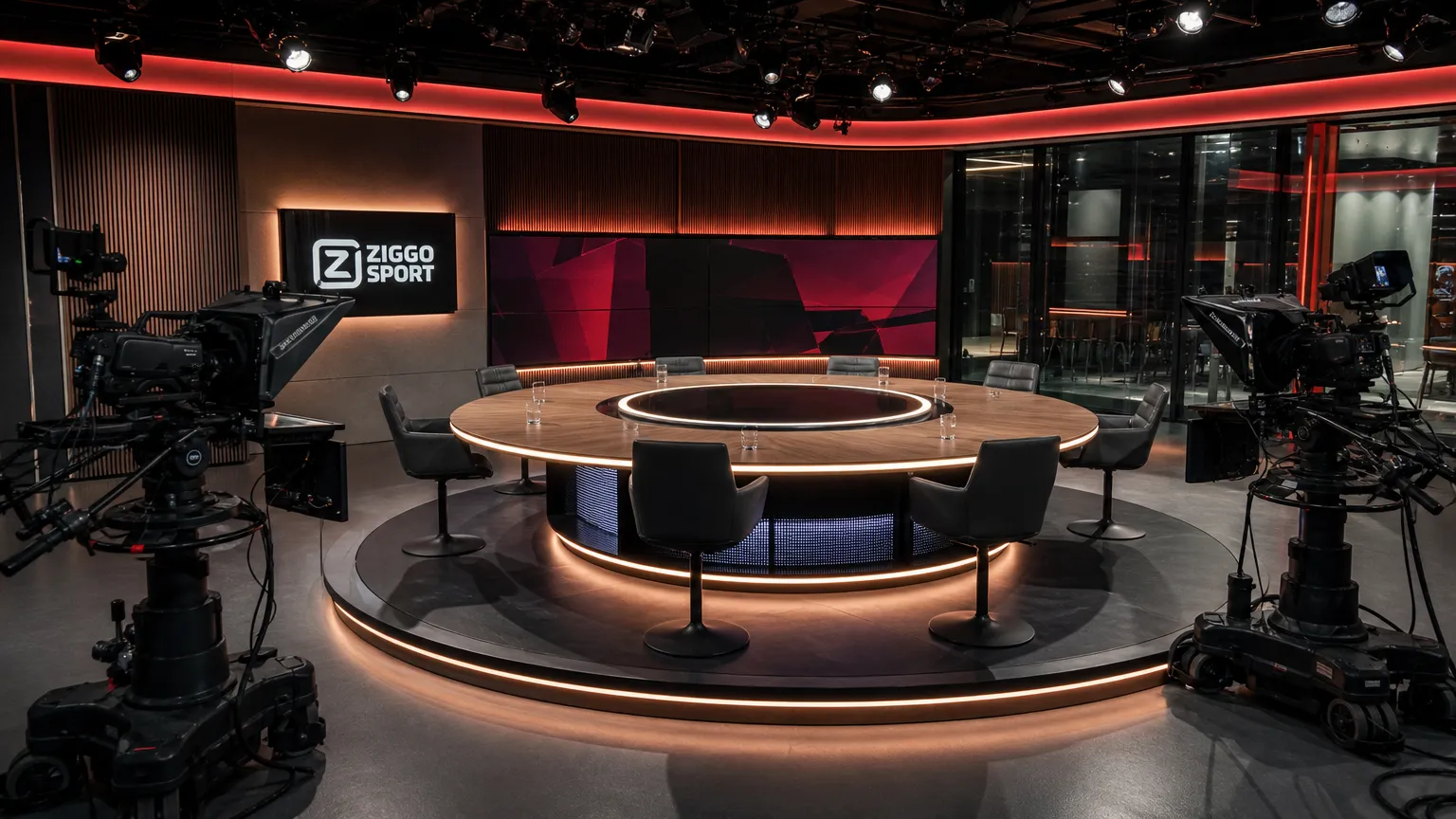 Een verlichte voetbaltelevisiestudio met camera's en een discussietafel.