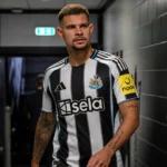 Voetbalcontext van Newcastle United in een spelerstunnel met clubkleuren op de achtergrond.