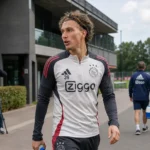 Ajax-trainingscomplex met medewerkers en camera’s bij de toegang tot het veld.