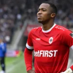 Willian Pacho in het rode tenue van Royal Antwerp FC aan de rand van een voetbalveld.