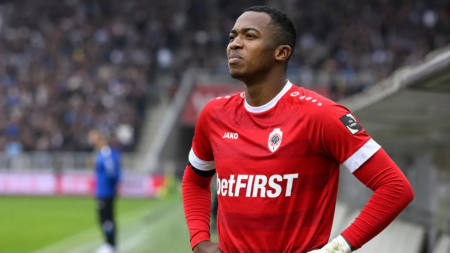 Willian Pacho in het rode tenue van Royal Antwerp FC aan de rand van een voetbalveld.