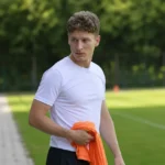Yari Verschaeren in neutrale sportkleding aan de rand van een voetbaltrainingsveld.