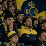 Union-supporters reageren gespannen in een volle stadiontribune.