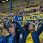 Supporters van SK Beveren met geel-blauwe sjaals in de tribune.