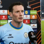 Rob Schoofs in het lichtblauwe shirt van Union tijdens een interview naast het veld.
