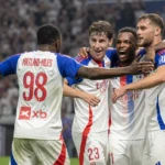 Een groep spelers van Olympique Lyon viert samen op het veld tijdens een Europese wedstrijd.