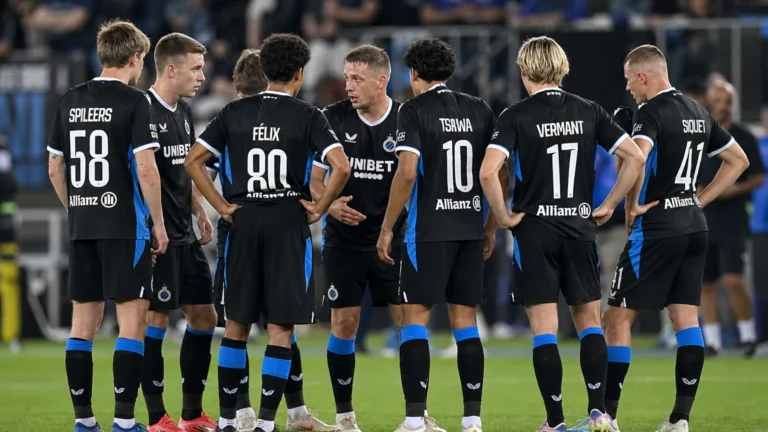 Club Brugge-spelers vormen een hechte kring op het veld in zwarte wedstrijdtenues.