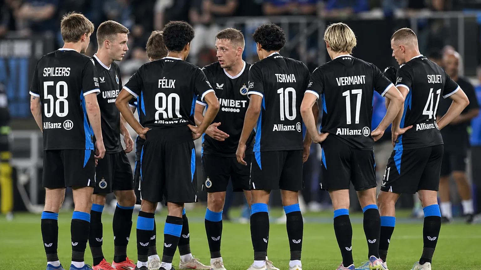 Club Brugge-spelers vormen een hechte kring op het veld in zwarte wedstrijdtenues.