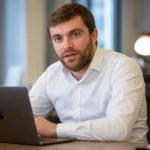 Fabrizio Romano in een rustige redactieruimte terwijl hij aan een laptop werkt.