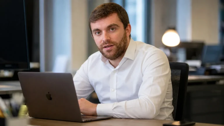 Fabrizio Romano in een rustige redactieruimte terwijl hij aan een laptop werkt.