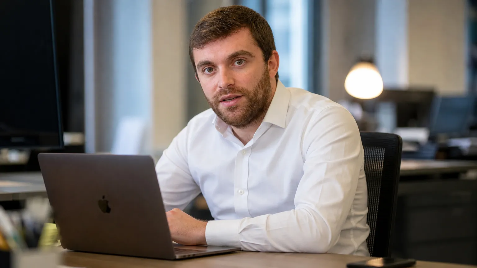 Fabrizio Romano in een rustige redactieruimte terwijl hij aan een laptop werkt.
