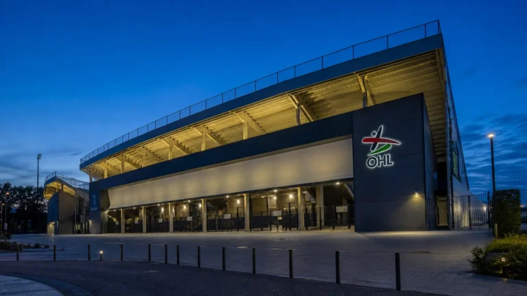 De buitenzijde van een voetbalstadion met een vaste OHL-signalisatie aan de gevel.