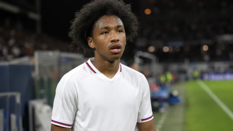 Malick Fofana in een wit voetbalshirt in een stadionomgeving.