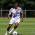 Tayo Adaramola controleert de bal op een trainingsveld in zijn Crystal Palace-kleding.