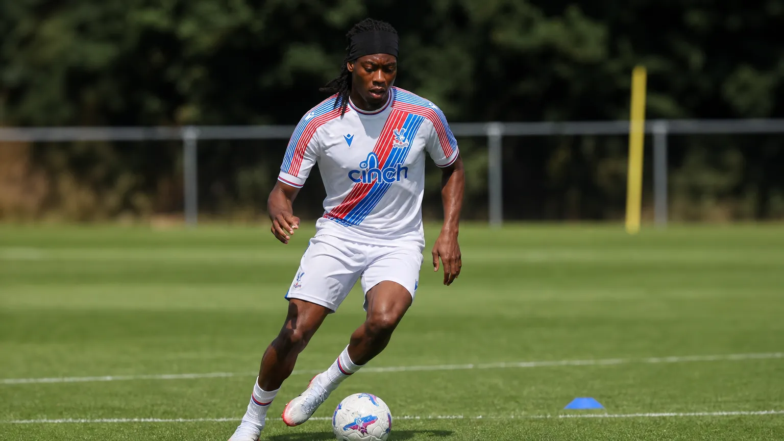 Tayo Adaramola controleert de bal op een trainingsveld in zijn Crystal Palace-kleding.