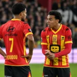 Twee spelers van KV Mechelen in rood-geel tenue op het veld.