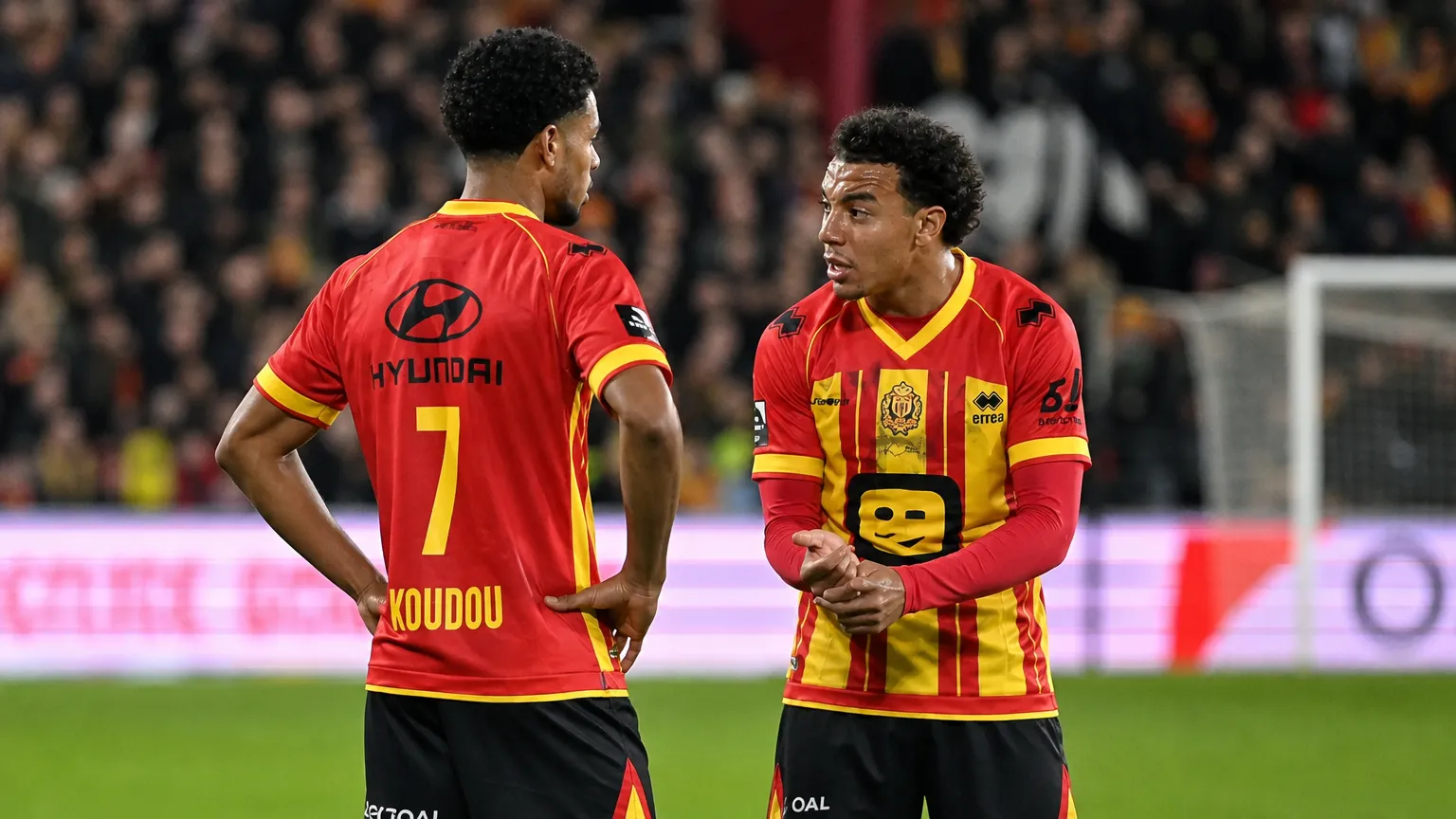 Twee spelers van KV Mechelen in rood-geel tenue op het veld.