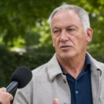 Marc Degryse spreekt tijdens een interview in een rustige buitenomgeving.