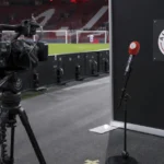 Een televisiecamera staat opgesteld in de interviewzone langs het veld van Ajax.