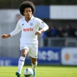 Joshua Nga Kana in een wit Anderlecht-tenue tijdens een voetbalmoment op het veld.