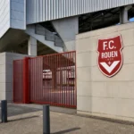 Ingang van het stadion van FC Rouen met een discreet clubbord.