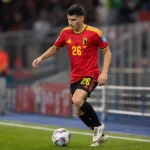 Matias Fernandez-Pardo warmt op in het tenue van de Rode Duivels in een voetbalstadion.