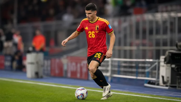 Matias Fernandez-Pardo warmt op in het tenue van de Rode Duivels in een voetbalstadion.