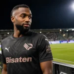 Salim Diakité in een donker Palermo-tenue aan de rand van een verlicht voetbalveld.
