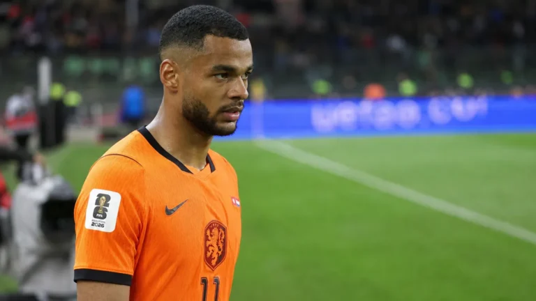 Cody Gakpo in het Nederlands elftalshirt tijdens een rustig moment langs het veld.