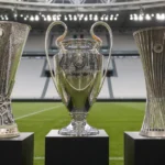 Drie Europese voetbaltrofeeën opgesteld in een neutrale voetbalomgeving.