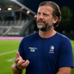 Rik De Mil van KAA Gent spreekt rustig naast een voetbalveld.