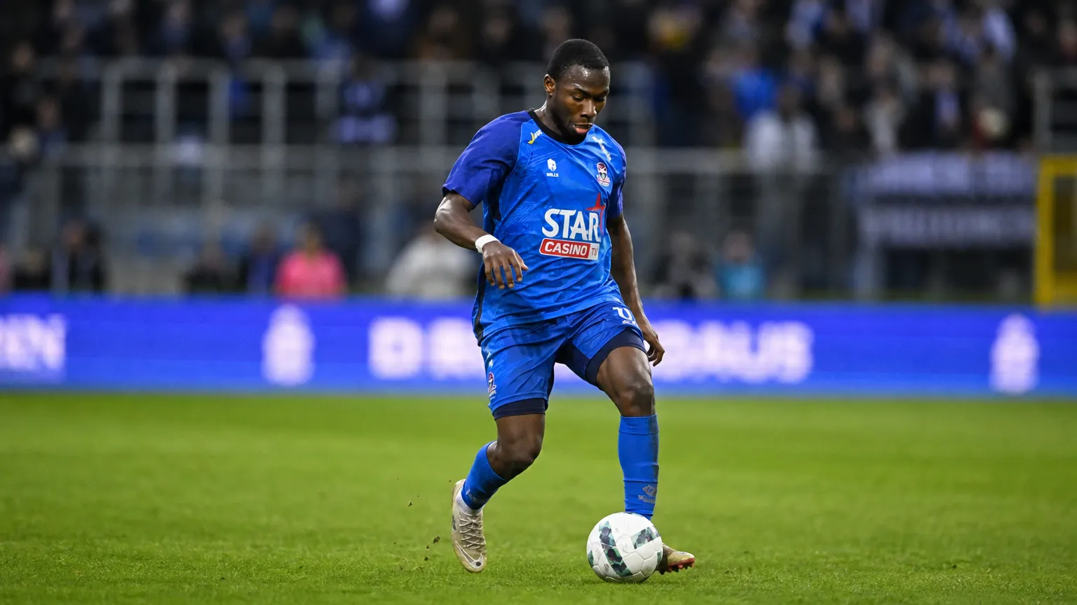 Mohamed Berte in blauw wedstrijdshirt tijdens een actie met de bal op het veld.
