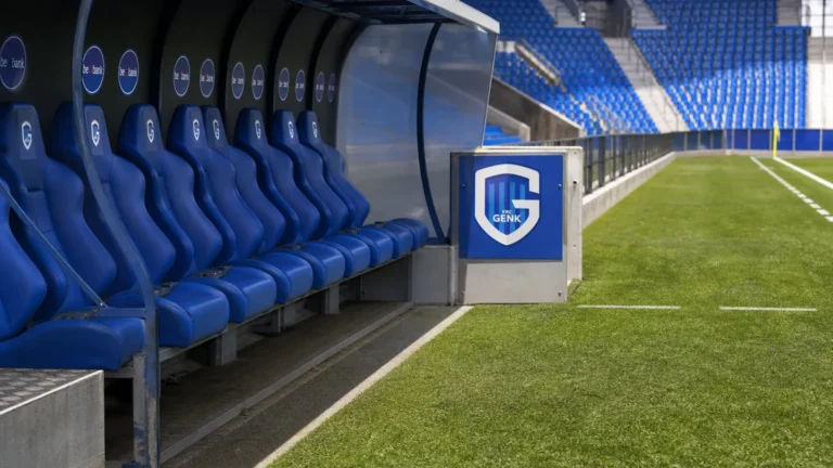 Lege technische zone langs het veld met een discreet KRC Genk-bord.