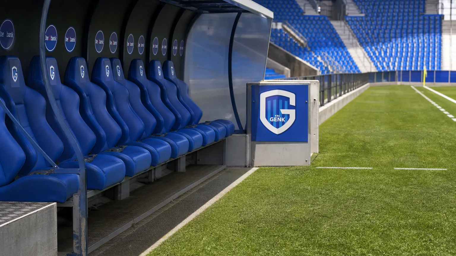 Lege technische zone langs het veld met een discreet KRC Genk-bord.