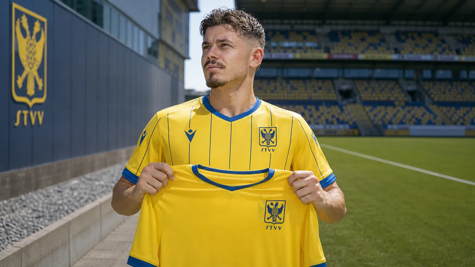 Arbnor Muja poseert met een geel STVV-shirt tijdens zijn officiƫle voorstelling.