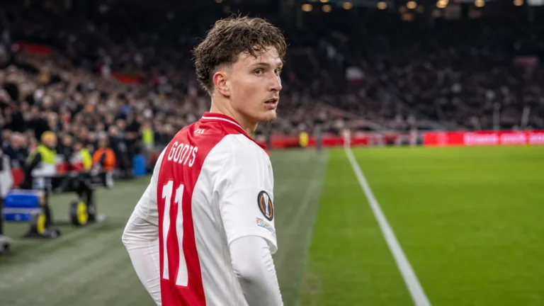 Mika Godts in het rood-witte tenue van Ajax aan de rand van het veld.