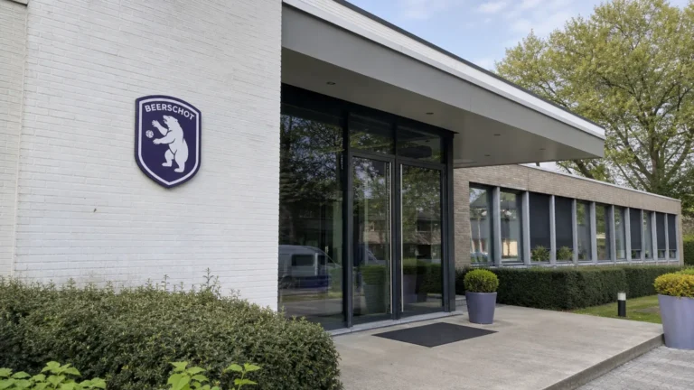 De ingang van een Beerschot-clubgebouw met een discreet clubembleem aan de gevel.