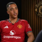 Youri Tielemans tijdens een voetbalinterview in een studio met een discreet Manchester United-wanddetail.