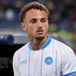 Noa Lang in een wit voetbalshirt in de technische zone van een stadion.