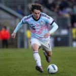 Denzel De Roeve in actie in een lichtblauw en roze voetbaltenue.