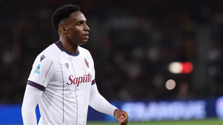 Jhon Lucumì in een wit voetbalshirt aan de rand van een verlicht veld