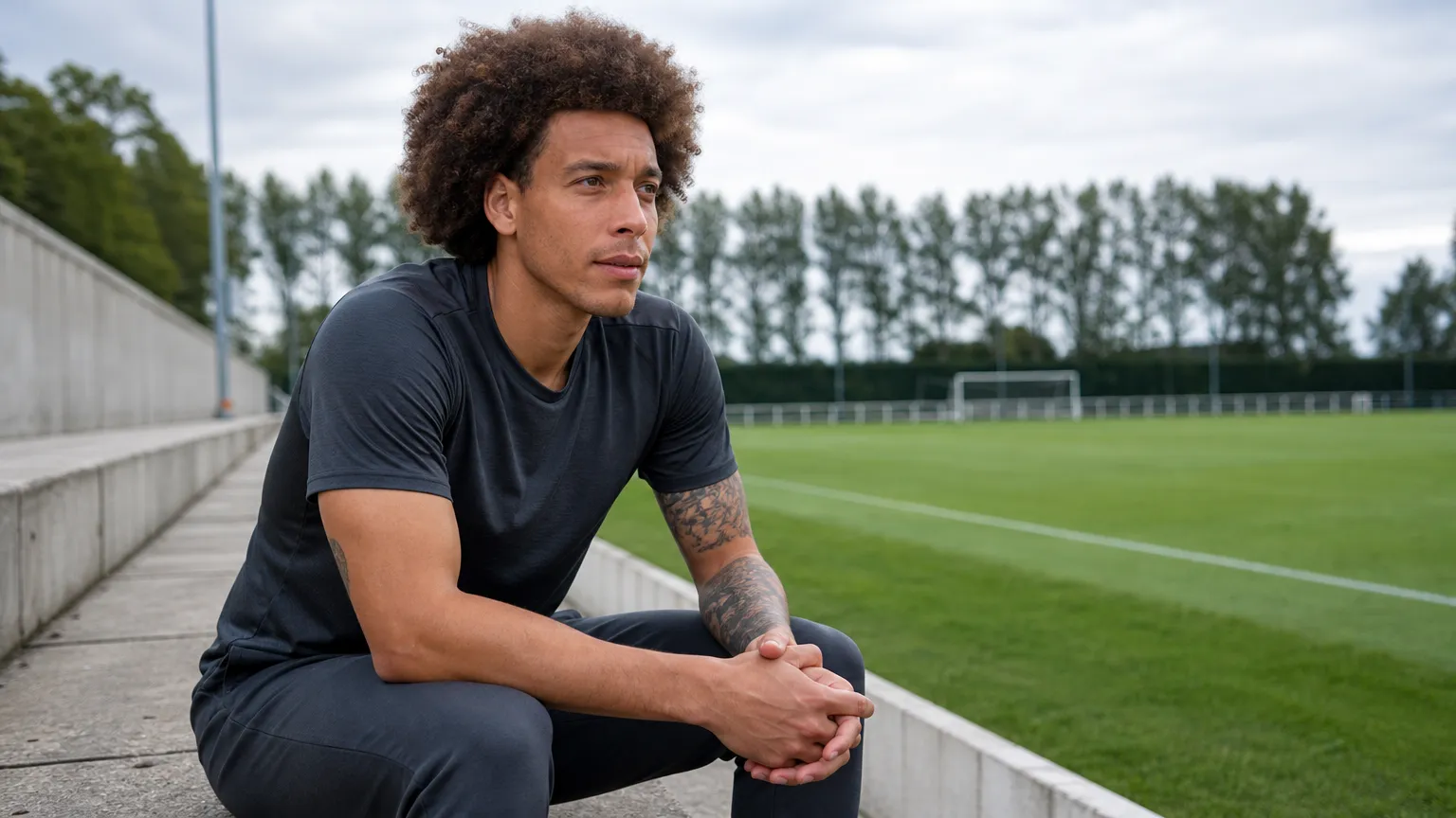 Axel Witsel in neutrale sportkleding aan de rand van een voetbalveld.