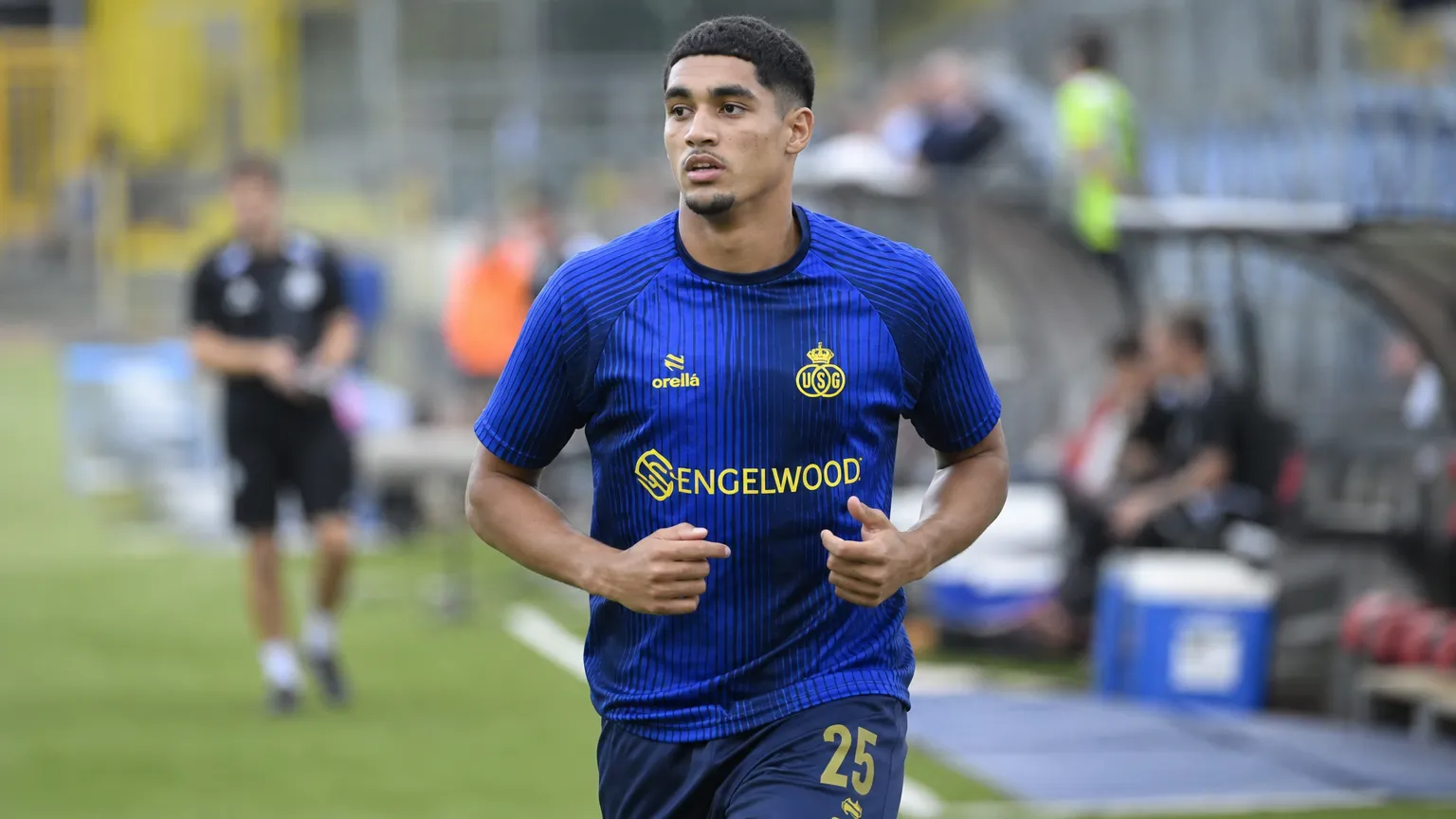 Anan Khalaili warmt op aan de rand van een voetbalveld in donkerblauw tenue.