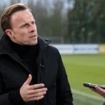 Vincent Euvrard spreekt rustig met een journalist naast het veld.
