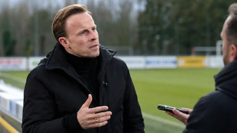 Vincent Euvrard spreekt rustig met een journalist naast het veld.