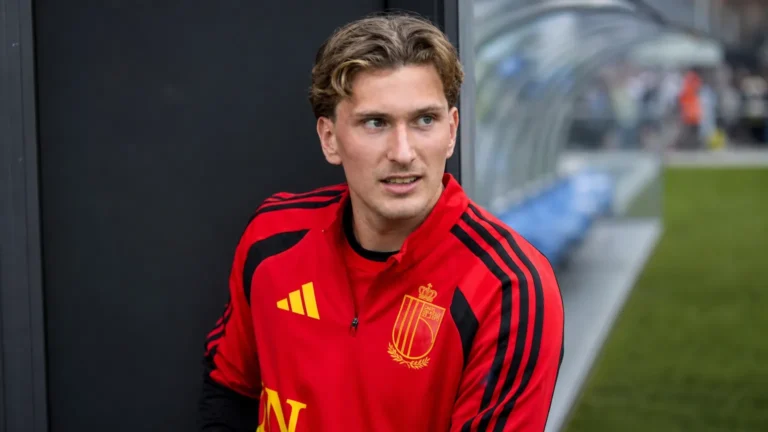 Mika Godts in een rode Belgische trainingstop in een neutrale gemengde zone naast het veld.