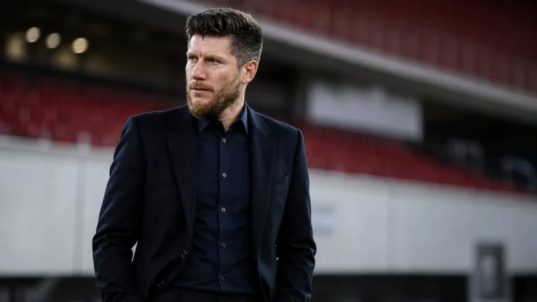 Sebastien Pocognoli in donkere formele kleding in een neutrale stadionperszone.